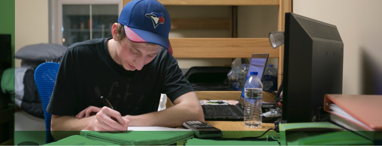 A student sitting in his dorm room doing homework.